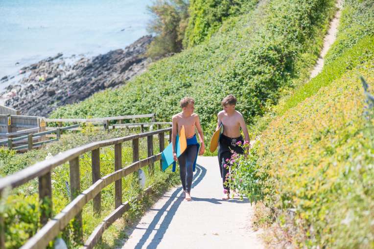 Two friends walking up the footpath with their belly boards